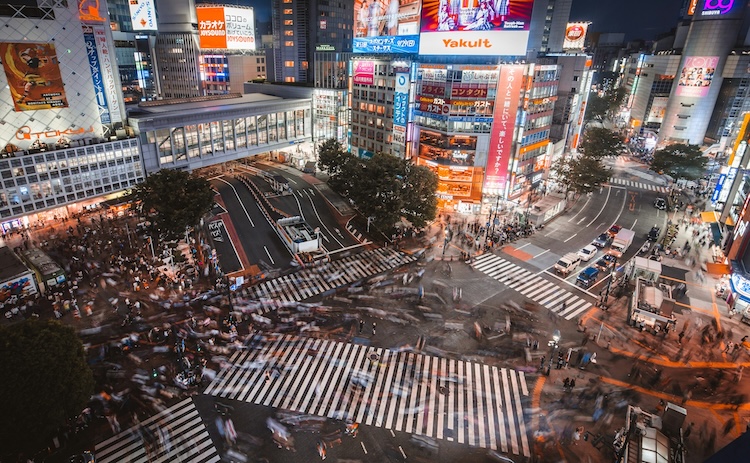 a busy street corner with multiple crosswalks at a slight time lapse so you can see the high movement of people